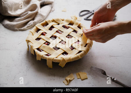 Non cotte torta di frutti di bosco con un reticolo di decorazione su top. Sfondo di calcestruzzo, il processo di cottura. Foto Stock