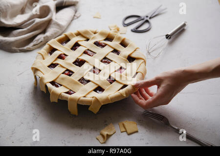 Non cotte torta di frutti di bosco con un reticolo di decorazione su top. Sfondo di calcestruzzo, il processo di cottura. Foto Stock