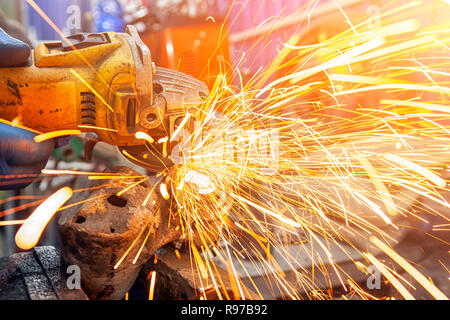 Close-up di un uomo taglio dei metalli con una mano la sega circolare su una tavola di legno, luminoso lampeggia battenti in direzioni diverse in background per strumenti Foto Stock