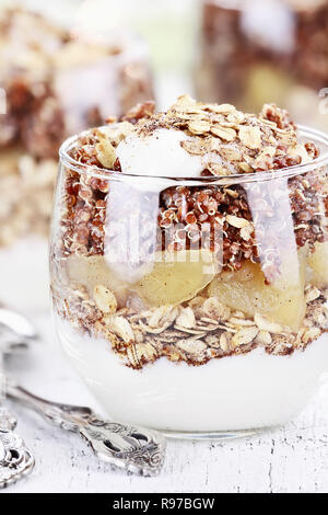 Tre bocce di rosso la quinoa con mele, yogurt e muesli con profondità di campo ridotta. Foto Stock