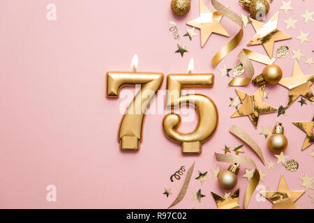 Numero 75 celebrazione oro candela su stella e glitter sfondo Foto Stock