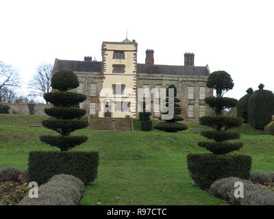 I motivi della proprietà del National Trust a Canons Ashby, Northamptonshire su un livello di grigio dicembre pomeriggio; vista di prati, topiaria da e Manor House Foto Stock