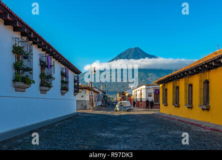 Un mototaxi passando per una strada che attraversa a sunrise nel centro storico della città di Antigua con il vulcano Agua in background, Guatemala. Foto Stock