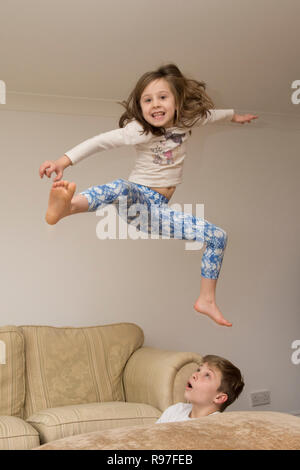 Bambini, fratello e sorella salta su mobili, immersioni subacquee e saltando, essendo iperattivo, lotti di energia, giocare insieme Foto Stock