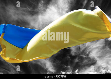 La luce del sole bandiera ucraino sventolare nel vento sul bianco e nero cielo tempesta Foto Stock