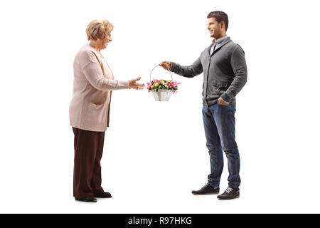 A piena lunghezza shot di un giovane uomo dando abasket di fiori per una donna anziana isolati su sfondo bianco Foto Stock