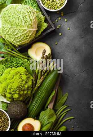 Assortiti nei toni del verde materie verdure organiche su sfondo scuro. Avocado, cavoli broccoli, cavolfiori e cetriolo con fagioli rifilati. Foto Stock