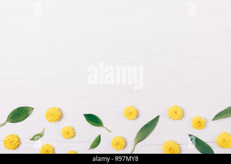Vista da sopra decorativo ornamento di fondo fatta di foglie verdi e piccolo giallo boccioli di fiori bianchi su sfondo di legno piana e composizione di laici con cop Foto Stock