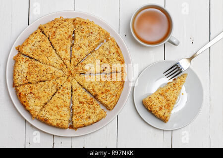 Torta fatta in casa con formaggio e mele, tazza di tè e la forcella su bianco tavolo in legno. Vista dall'alto. Foto Stock