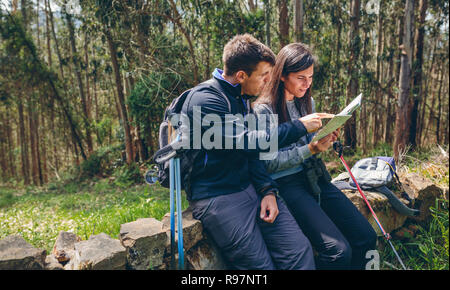 Giovane facendo trekking seduta guardando una mappa Foto Stock