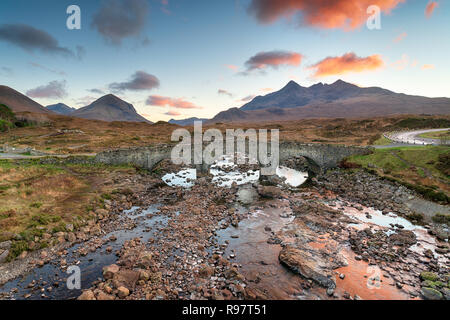 Il tramonto del vecchio ponte di Sligachan sull'Isola di Skye in Scozia con le montagne Cuillin in background Foto Stock