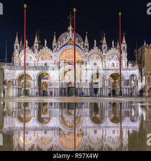 Basilica di San Marco a Venezia con la riflessione di notte durante l'alta marea, o aqua alta, che ha allagato il quadrato con acqua di mare Foto Stock