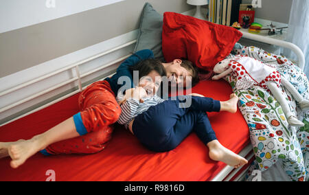 Fratelli solletico e ridere giacente sul letto Foto Stock
