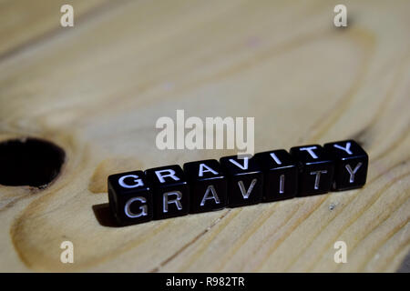 Gravità scritto su blocchi di legno. Ispirazione e motivazione concetti. Croce immagine elaborata su sfondo di legno Foto Stock
