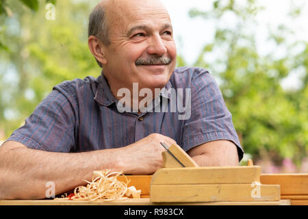 Carpenter lavora con piano su sfondo di legno Foto Stock