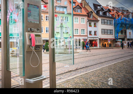 Freiburg im Breisgau, Germania - 31 dicembre 2017: pubblico cabina telefonica sulla strada dove le persone sono a piedi su una giornata invernale Foto Stock