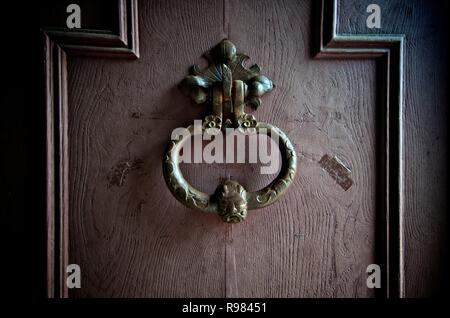 Close up di un ferro battuto respingente scolpito su un marrone porta di legno. Francia Foto Stock