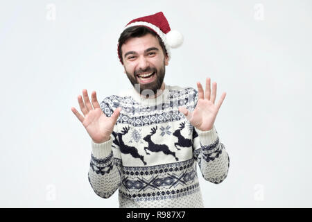 Guy nel cappello di Natale sorridente ampiamente da gioia gesticolando con palme battendo le mani Foto Stock