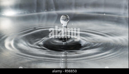 Acqua goccia caduta in acqua facendo a cerchi concentrici Foto Stock