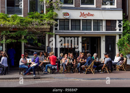 I giovani seduti e bere fuori Libertine Cafe a Amsterdam, Paesi Bassi Foto Stock