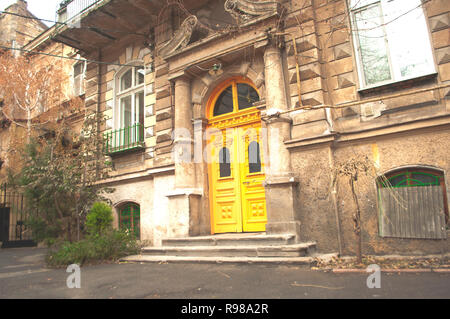 Il vecchio cortile affascinante con in Odessa, Ucraina. Ingresso in un vecchio edificio con colore giallo brillante porta. Foto Stock