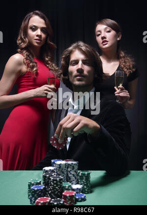L uomo alla roulette tavolo circondato da belle donne Foto Stock