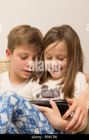 Dispositivo digitale, tablet, iPad fratello con la sorella più giovane giochi sul dispositivo elettronico. Foto Stock
