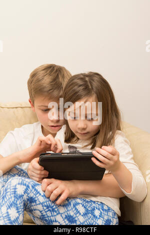 Dispositivo digitale, tablet, iPad fratello con la sorella più giovane giochi sul dispositivo elettronico. Foto Stock