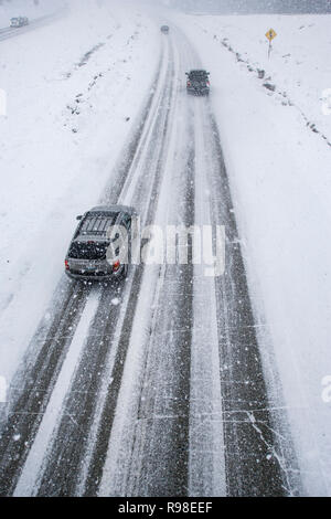 Un overhead shot guardando verso il basso su una superstrada strada ghiacciata in condizioni di innevamento. Questo è Snoqualmie Pass su I90 oltre la cascata le montagne in inverno. Foto Stock