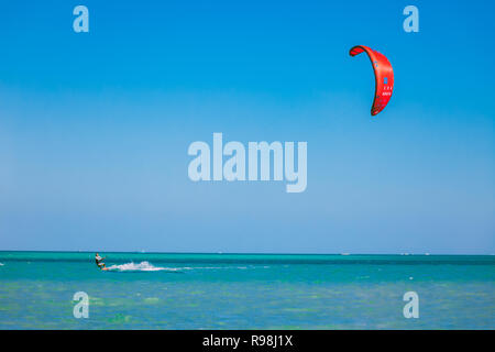 Egitto, Hurghada - 30 Novembre, 2017: Il kitesurfer con aquilone rosso di scorrimento sul mare rosso superficie. Schiacciante paesaggi marini. Il lone kiteboarder Foto Stock