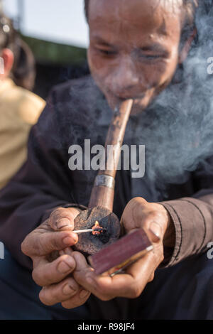 Il Meghalaya, India - 12 Maggio 2017: Khasi uomo fumatori tradizionale di un lungo tubo con il tabacco Foto Stock