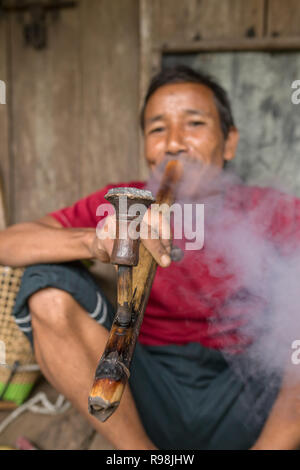 Il Meghalaya, India - 15 Maggio 2017: Khasi uomo fumatori tradizionale di un lungo tubo con il tabacco Foto Stock