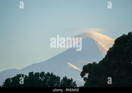 I colori del tramonto sul ghiacciaio del vulcano Osorno, con la formazione di nubi al suo vertice Foto Stock