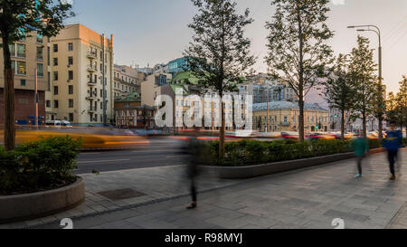 Il flusso di pedoni e automobili seguendo la strada di città Foto Stock