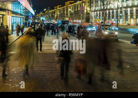 Il flusso di pedoni e automobili seguendo la strada di città Foto Stock