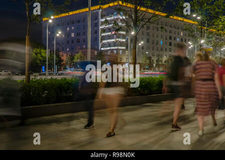 Il flusso di pedoni e automobili seguendo la strada di città Foto Stock