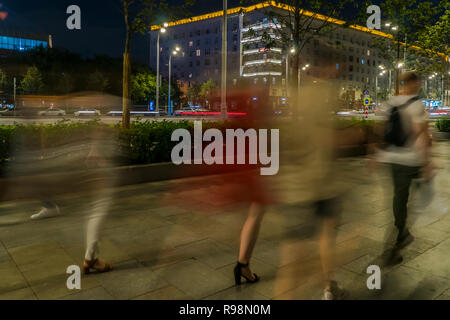 Il flusso di pedoni e automobili seguendo la strada di città Foto Stock