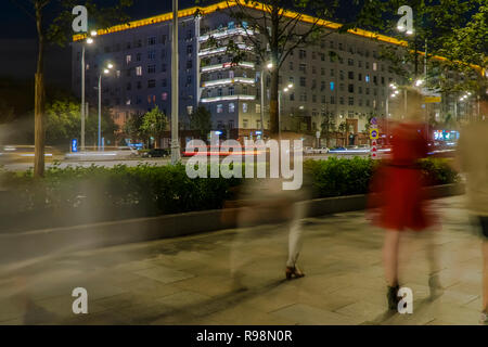 Il flusso di pedoni e automobili seguendo la strada di città Foto Stock