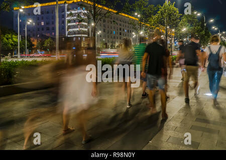 Il flusso di pedoni e automobili seguendo la strada di città Foto Stock