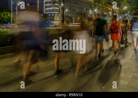 Il flusso di pedoni e automobili seguendo la strada di città Foto Stock