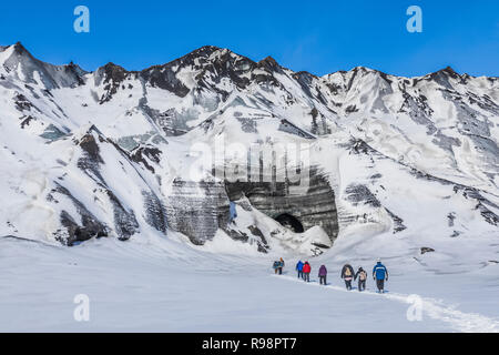 Avventurieri a camminare verso una caverna di ghiaccio in ingresso un lobo del ghiacciaio Mýrdalsjökull, che siede in cima al vulcano Katla, in inverno in Islanda [Nessun modello rele Foto Stock