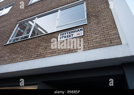 Cerca in corrispondenza della zona di spigolo di un edificio in mattoni che mostra un Tottenham Street London street nome sign in alto su una parete di mattoni Foto Stock