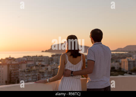 Coppia giovane in estate outfit godendo di una vista sulla città dalla terrazza sul tetto in Alanya in Turchia. Foto Stock