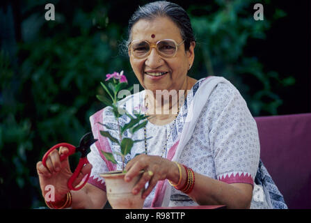 Vecchia donna senior impianto di trimming pentola floreale lavora in giardino - signor#319 Foto Stock