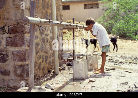 Uomo di bere acqua dal rubinetto comunitario, di approvvigionamento idrico nelle zone rurali, India Foto Stock