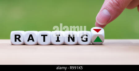 È a mano ruotando un dado e cambia la direzione di una freccia che simboleggia che la valutazione è positiva (o viceversa) Foto Stock