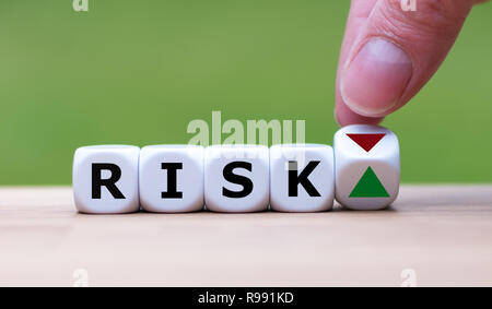 È a mano ruotando un dado e cambia la direzione di una freccia che simboleggia che il rischio sta in alto (o viceversa) Foto Stock