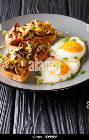 Una sana colazione a base di pane tostato con funghi shiitake e il formaggio cheddar e uova fritte close-up su una piastra sul piano verticale. Foto Stock