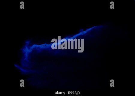 Blu di sabbia colorata esplosione isolata su sfondo nero. Abstract blue sand cloud. Blu di sabbia colorata schizzare contro su sfondo scuro. Foto Stock