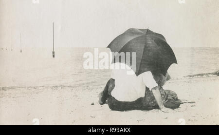 Antiquariato fotografia 1908, Vittoriano giovane sotto un ombrellone sulla spiaggia. Posizione sconosciuta, STATI UNITI D'AMERICA. Fonte: fotografia originale Foto Stock